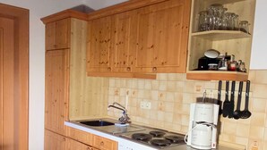 Une cuisine de taille réduite, dotée de meubles en bois, d’une cuisinière et d’une machine à café.
