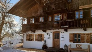 Ein traditionelles Holzchalet mit Balkon, einer Holztür und einer Bank davor.