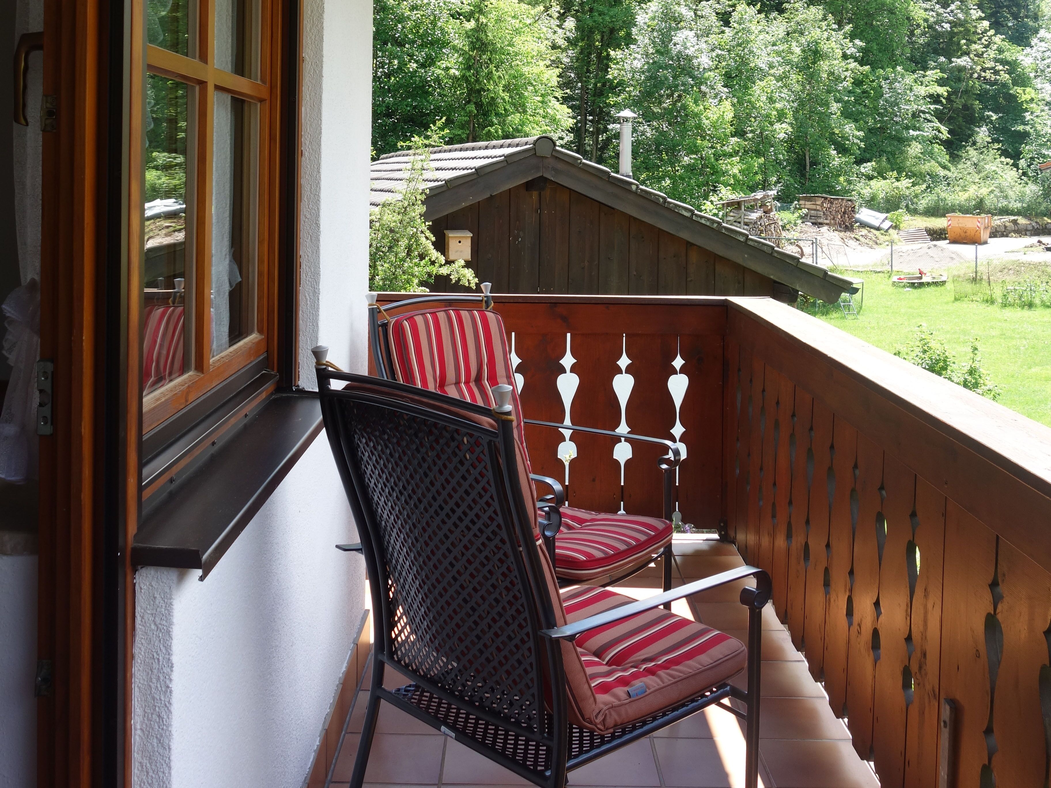 Ein Balkon mit Holzbalkon, einem Stuhl und einem Fenster.