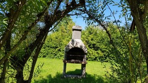 A stone-built outdoor oven surrounded by lush greenery and trees. - Predigtstuhl vacation apartment in a rural setting, 55 m², 1 bedroom (Bayerisch Gmain)