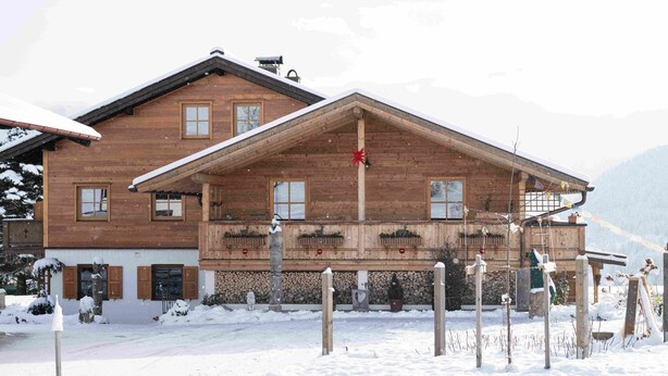 A wooden chalet with a balcony, surrounded by snow. - One-room apartment Weitblick with shower/WC and balcony (Reit im Winkl)