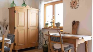 A wooden dining table with chairs, a wooden cabinet, and a wall clock. - One-room apartment Weitblick with shower/WC and balcony (Reit im Winkl)