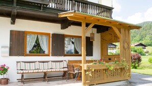 A wooden outdoor seating area with a bench and a table, surrounded by potted plants. - One-room apartment Weitblick with shower/WC and balcony (Reit im Winkl)