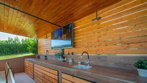 Une cuisine moderne avec un lambris en bois, un évier en acier inoxydable et un téléviseur encastré.
