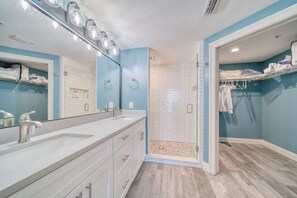 A modern bathroom with a large mirror, dual sinks, and a walk-in shower.