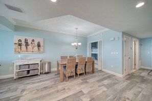 A dining area with a table and chairs, a chandelier, and a wall-mounted picture.