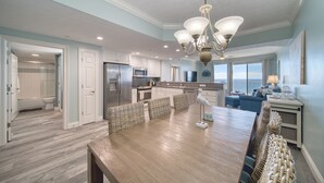Una cocina amplia con una isla grande, muebles blancos y vistas al exterior.