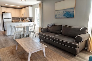 Ein modernes Wohnzimmer mit einer Couch, einem Couchtisch und einem Essbereich mit Stühlen.