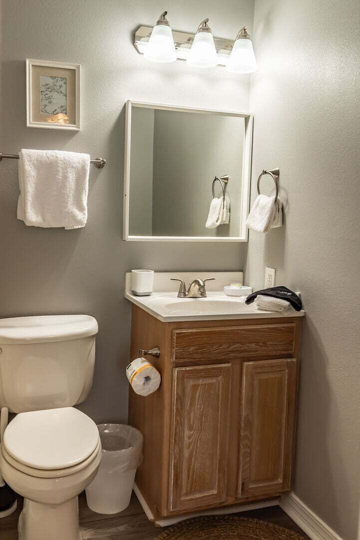 Un baño con inodoro, lavamanos, espejo y toallero.