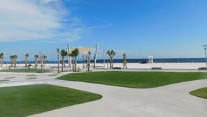 Un parque junto a la playa con senderos, palmeras y sombrillas.