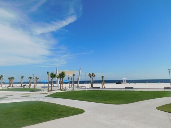 Ein Park am Strand mit Wegen, Palmen und Strandsonnenschirmen.