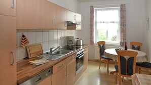Una cocina con armarios de madera, un lavamanos, una estufa y un comedor con mesa y sillas.