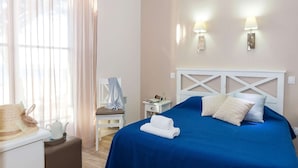 A hotel room with a bed, a chair, a table with a teapot, and two wall-mounted lamps. - Apartment in La Baule Near Cote D'amour (Pornichet)
