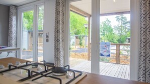 Een keuken met een gasfornuis, een houten tafel en grote schuifdeuren die uitkomen op een terras.
