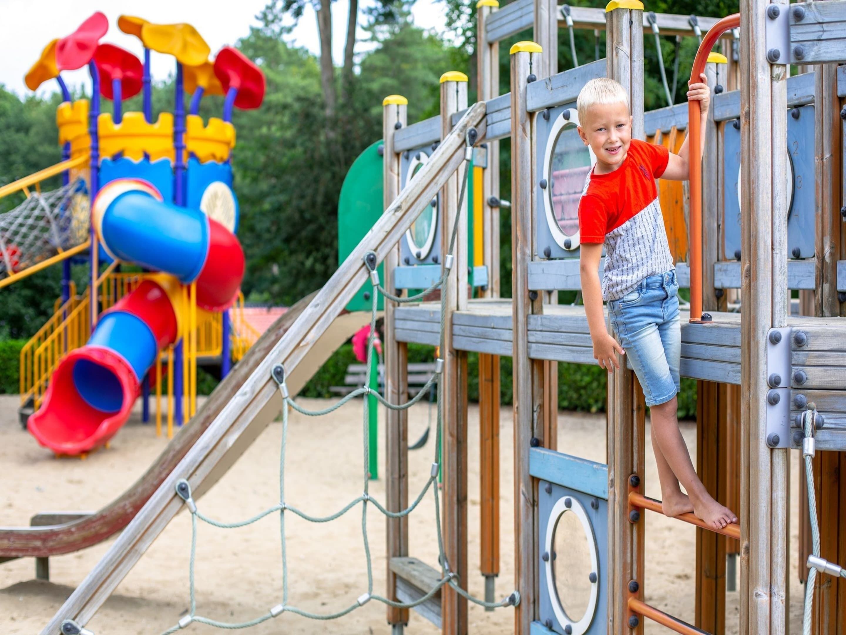 A child climbing a playground structure with multiple levels and slides.