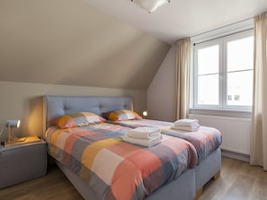 Une chambre à coucher avec un lit, une table de chevet et une fenêtre.