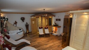 Ein gemütliches Zimmer mit Kamin, Holzböden und zwei Liegesesseln.