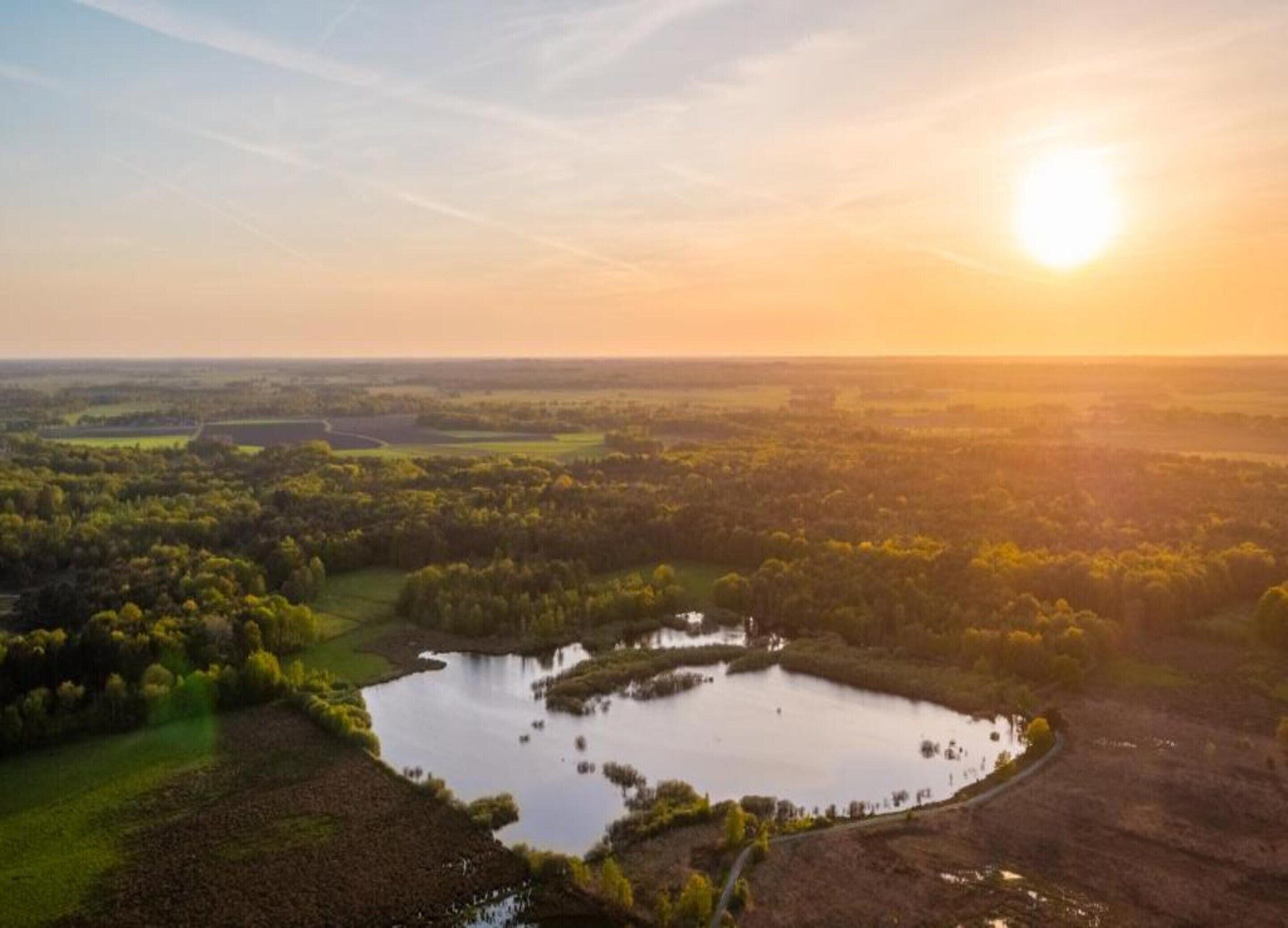 A landscape with a large body of water surrounded by greenery and fields.