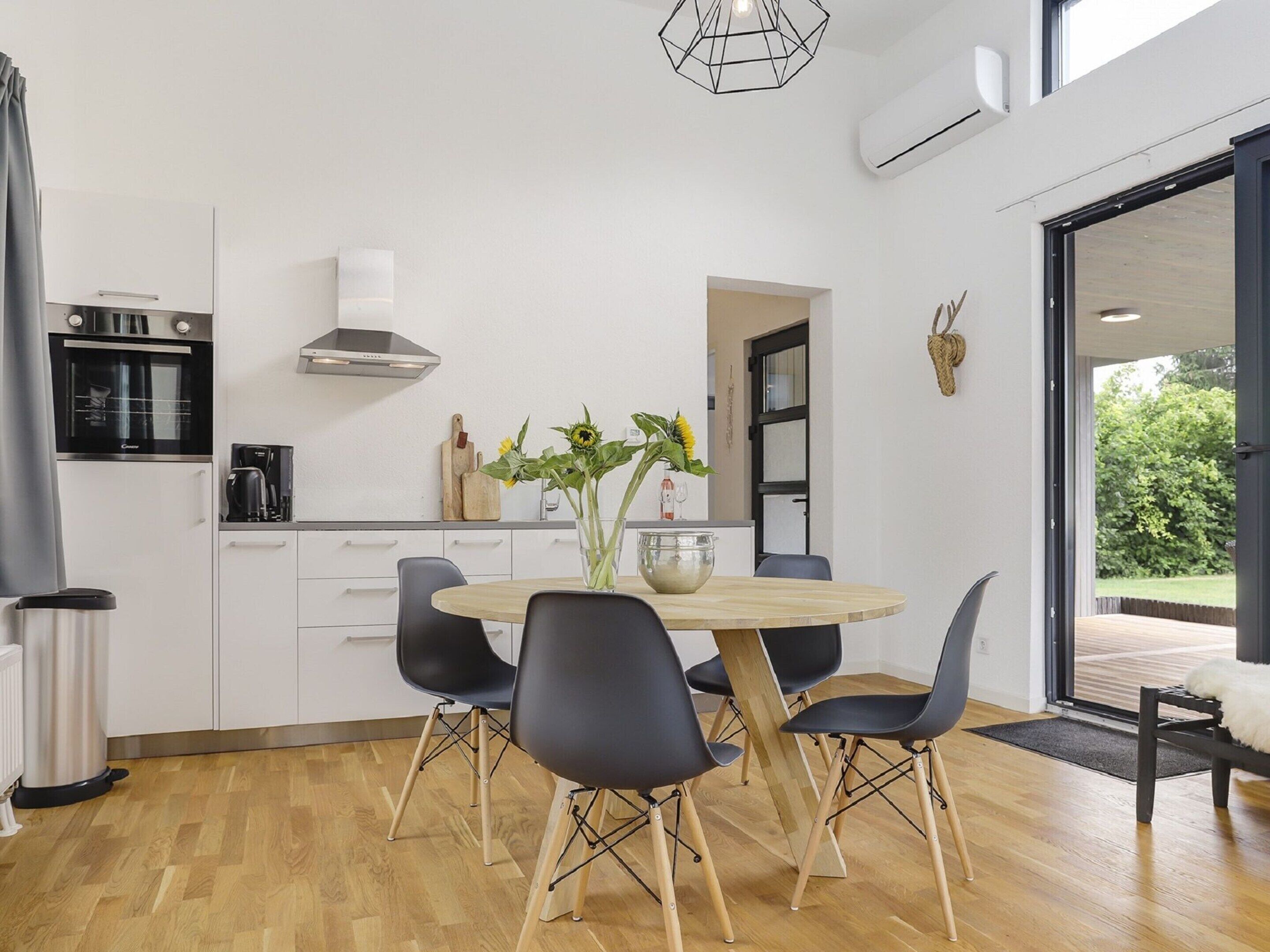 A modern kitchen with white cabinets, a round wooden table, and black chairs.
