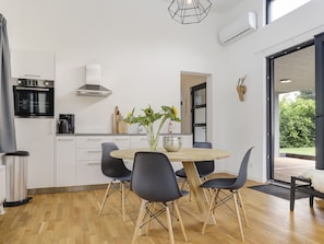 A modern kitchen with white cabinets, a round wooden table, and black chairs. - Stylish Escape in Enter (Enter)