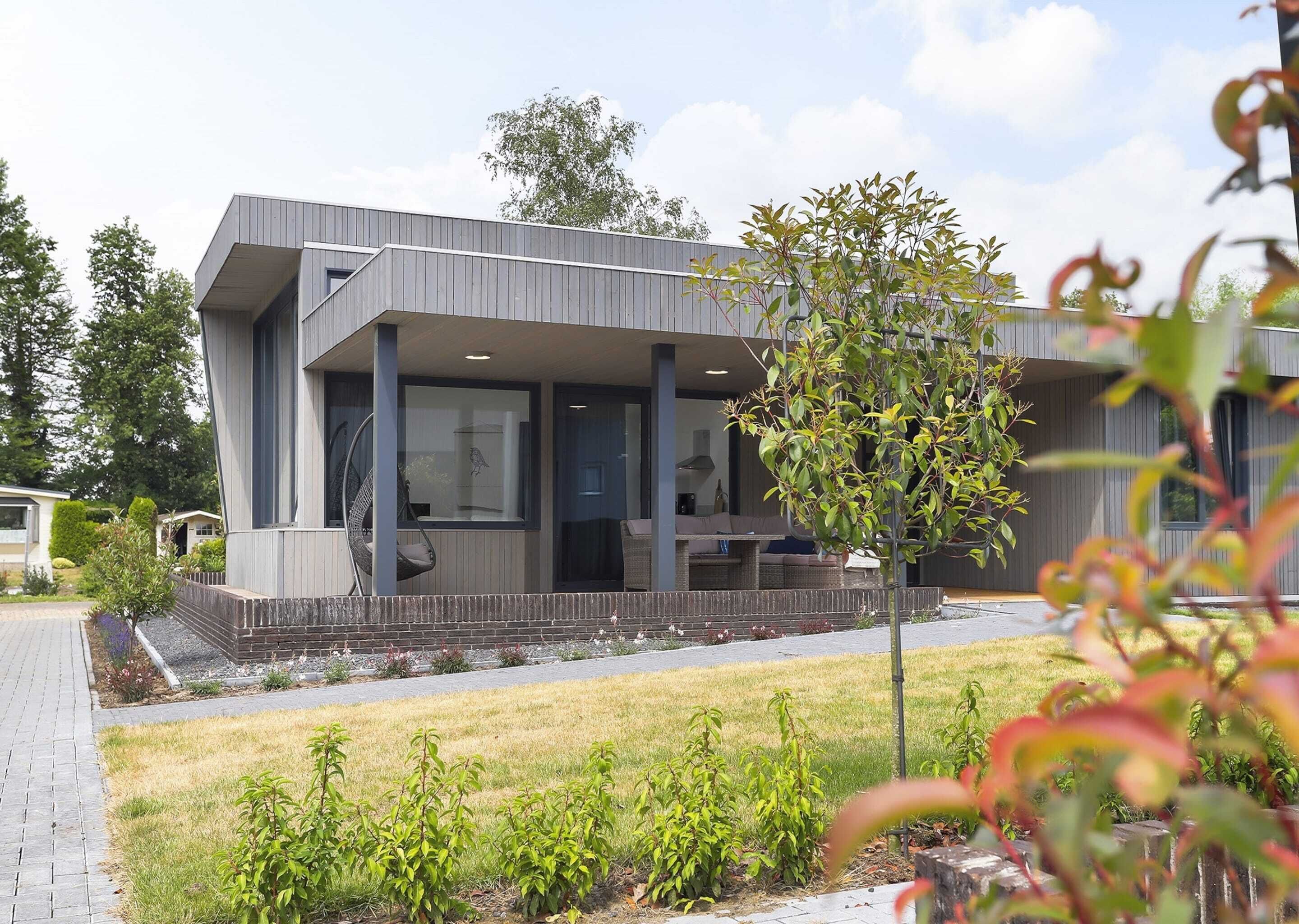 A modern building with a flat roof, large windows, and a covered outdoor seating area.