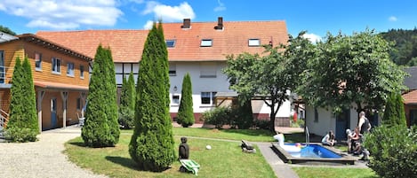 A courtyard with a swimming pool, surrounded by buildings with red-tiled roofs and neatly trimmed trees.