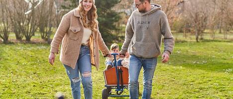 A family walking in a park with a child in a wagon.