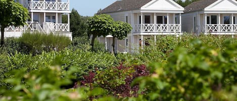 Une rangée de maisons blanches dotées de balcons, entourées d’une végétation luxuriante.