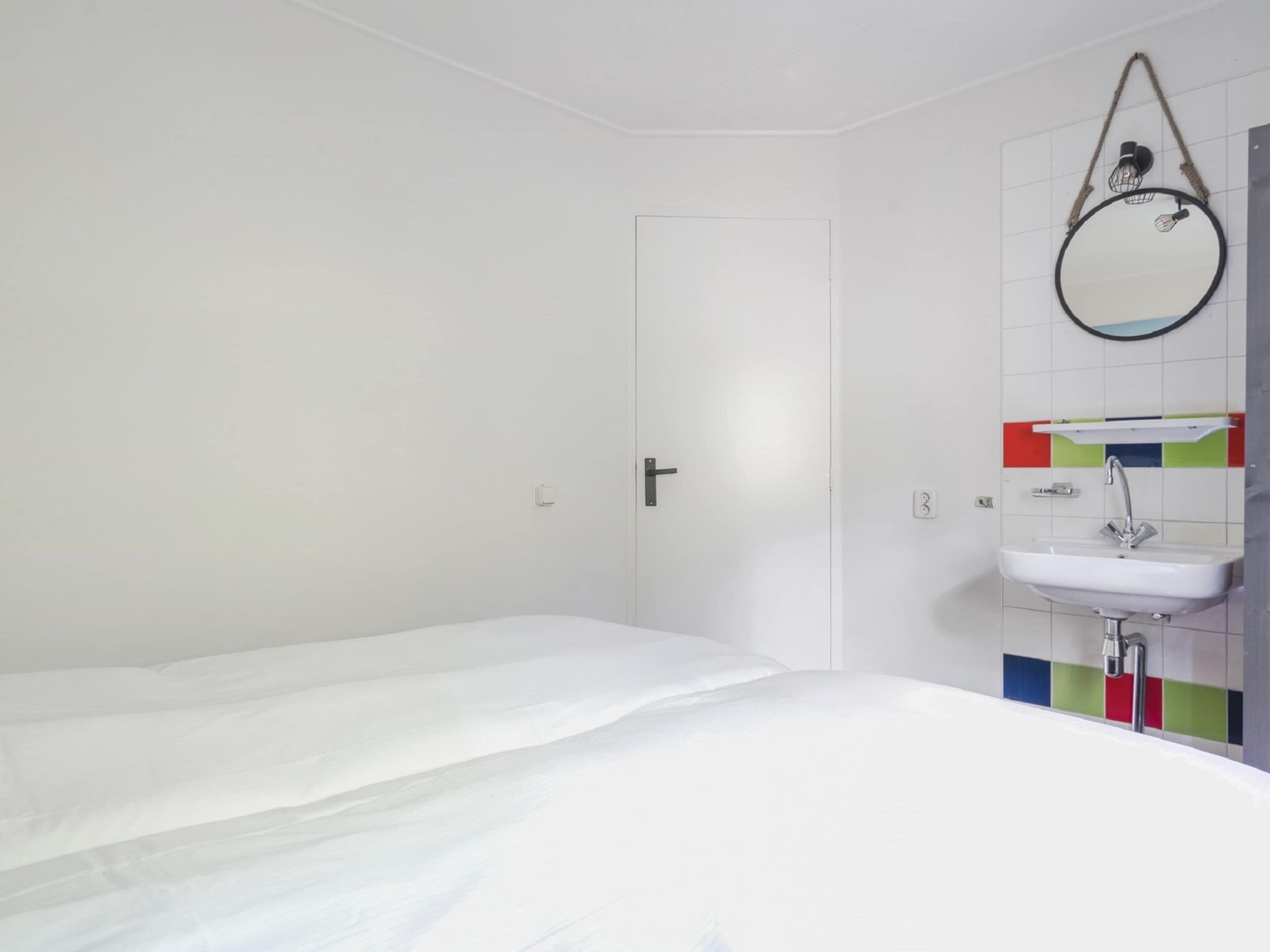 Ein helles, modernes Badezimmer mit Waschbecken, Spiegel und Tür.