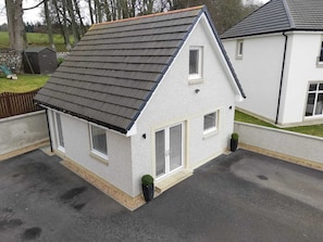 Ein kleines, eingeschossiges Haus mit Satteldach, einer Veranda und einer Garage.