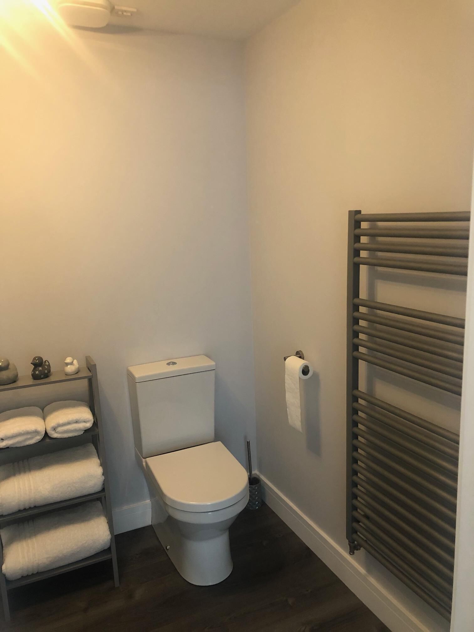 A small, clean bathroom with a toilet, a towel rack with towels, and a radiator.