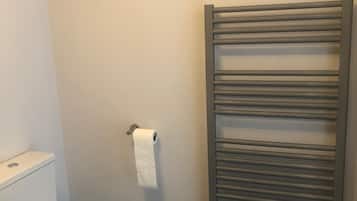 A bathroom with a toilet, a towel rack, and a wooden floor.