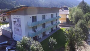 A multi-story building with a balcony, a sign advertising skiing, and a view of mountains in the background. - Apartment in Kleinarl Near Ski Lift (Kleinarl)