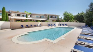 A swimming pool with lounge chairs, a building with balconies, and a clear sky. - Apartment in Bonnieux Near Lavender Fields (Bonnieux)
