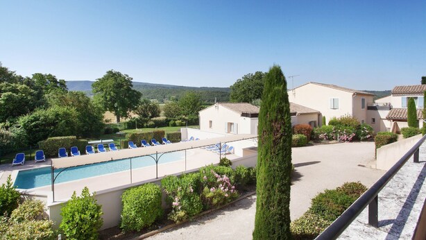 A pool with lounge chairs, a clear sky, and buildings in the background. - Apartment in Bonnieux Near Lavender Fields (Bonnieux)