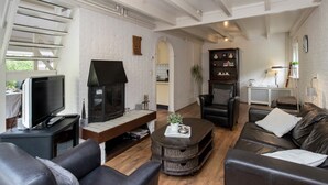 A modern living room with a fireplace, leather sofas, a television, and a bookshelf. - Cozy Holiday Home in Noordwijkerhout near Lake (Noordwijkerhout)