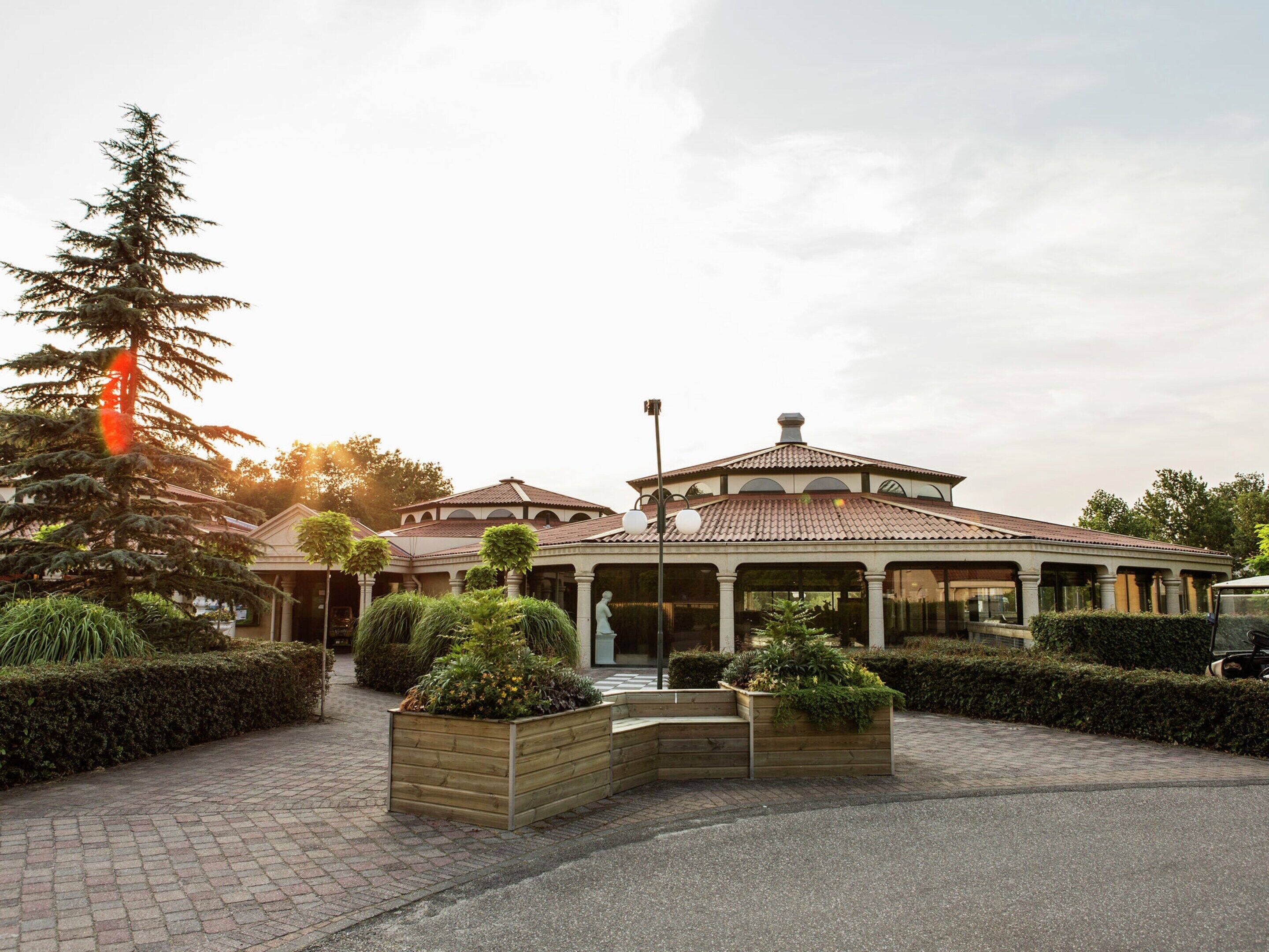 A building with a tiled roof, a covered entrance, and a paved walkway.