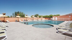 A swimming pool with sun loungers and umbrellas, surrounded by a tiled patio. - Nice Apartment Near Aigues-mortes (Aigues-Mortes)