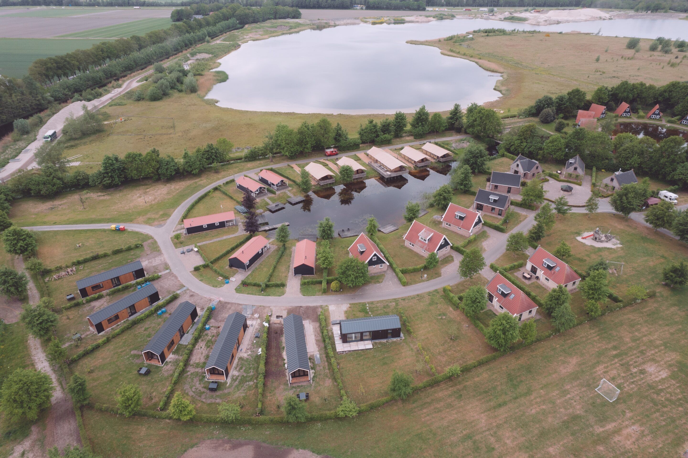 An aerial view of a lakeside residential area with houses, a road, and a large body of water.