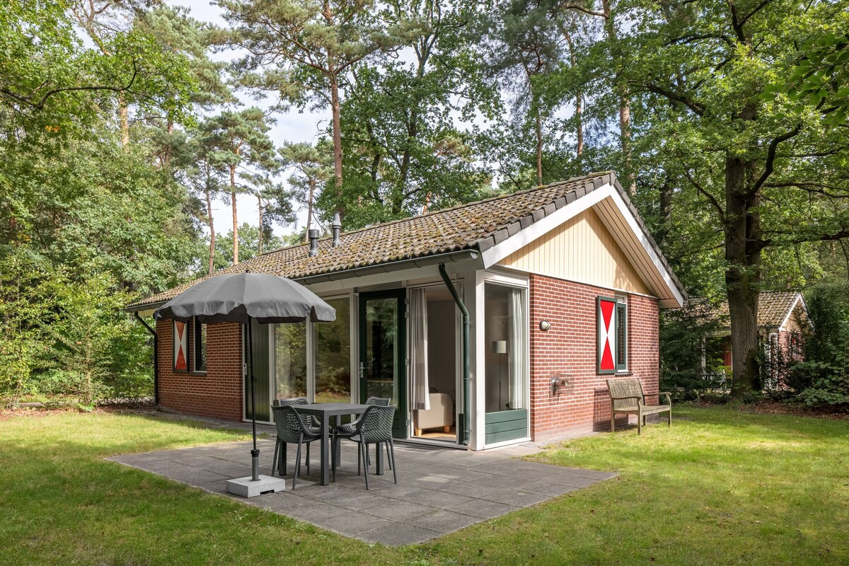 A small brick house with a patio, a table with chairs, and a covered outdoor seating area.