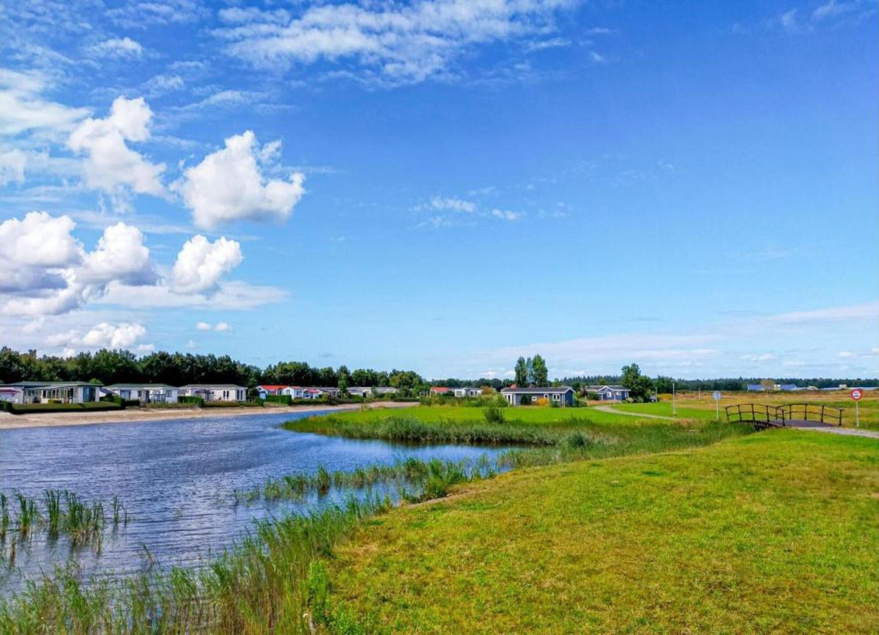 A riverside view with a bridge, grassy areas, and several buildings.