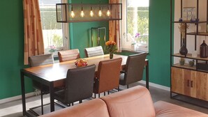 A dining area with a wooden table, leather chairs, and a vase of flowers. - Nice Holiday Home with Sauna & Hot Tub near Wadden Sea (Tzummarum)