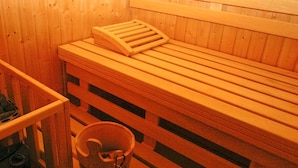 Een houten sauna bank met een ribbenhouten zitgedeelte en een klein houten doosje erop.