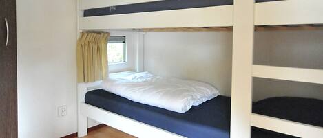 Une chambre avec un lit superposé, une fenêtre et des rideaux.