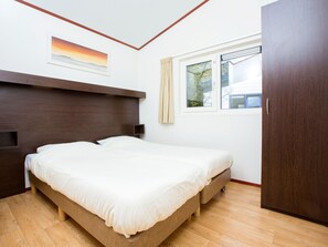 Relax in a serene space with a large bed, bedside table, and window with curtains.