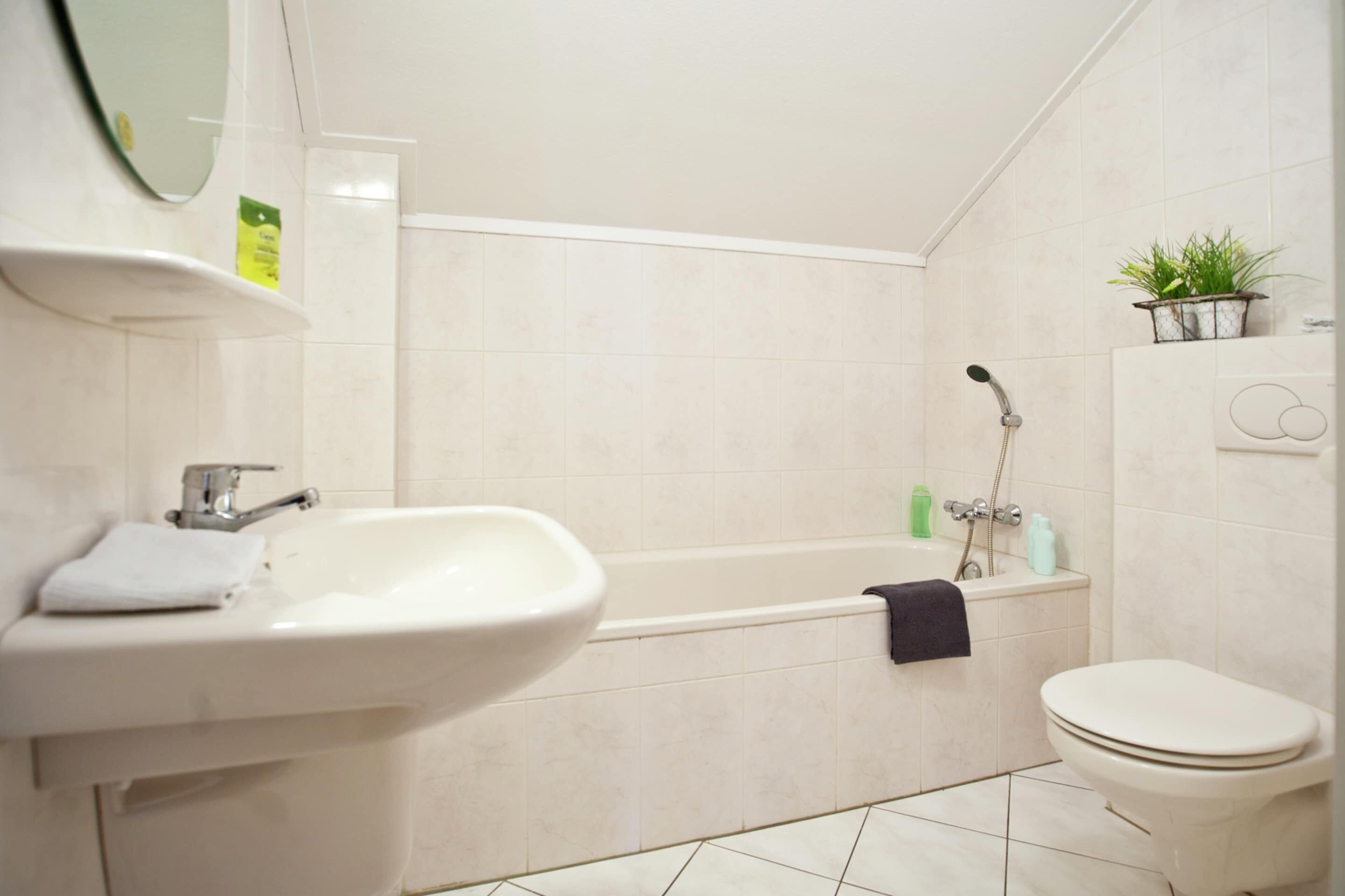 A bathroom with a sink, toilet, bathtub, and a mirror.