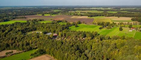 Luftaufnahme einer ländlichen Landschaft mit Feldern, Bäumen und verstreuten Gebäuden.