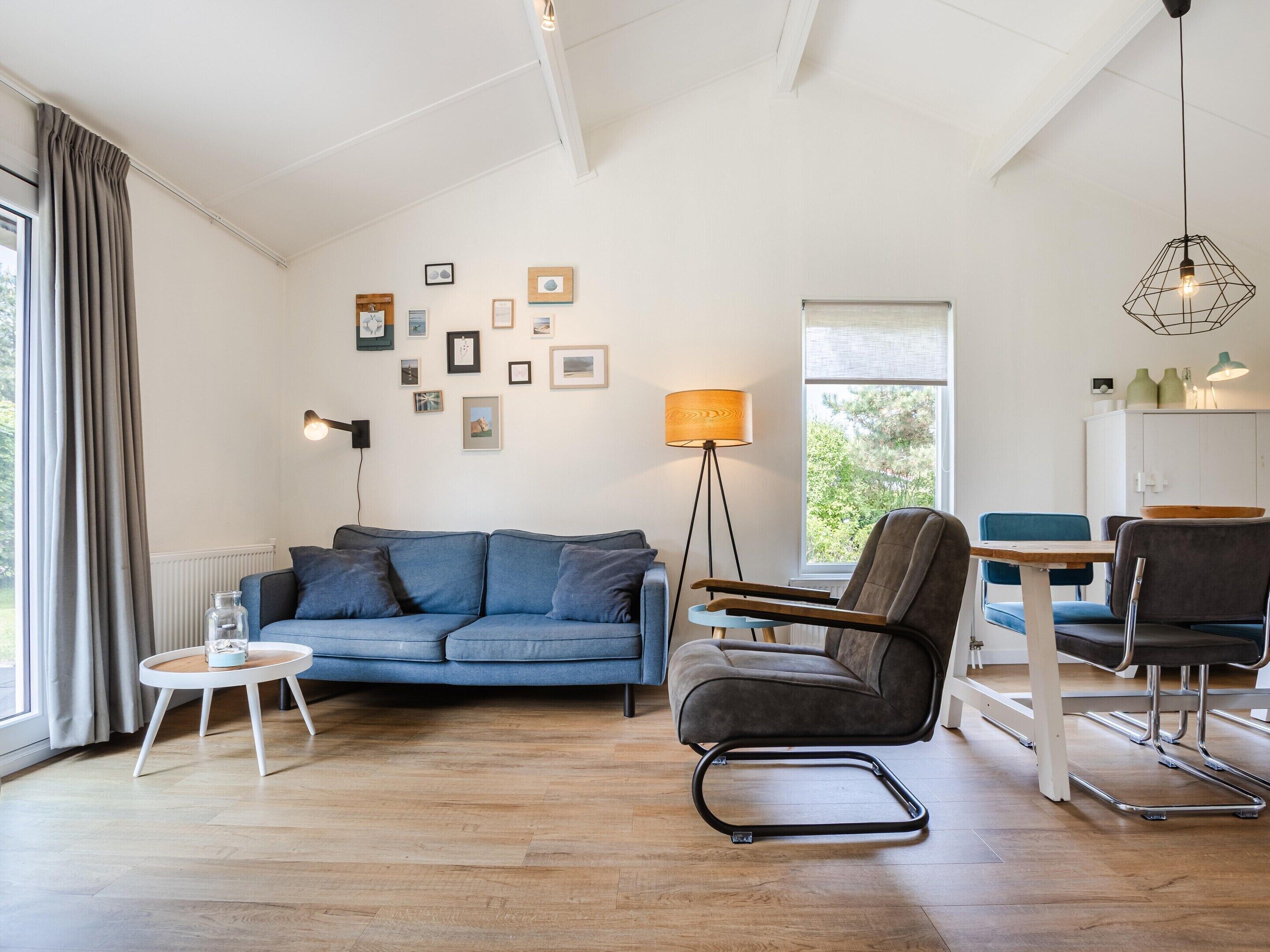 Un salon moderne avec un canapé, un fauteuil, une petite table et un lampadaire.