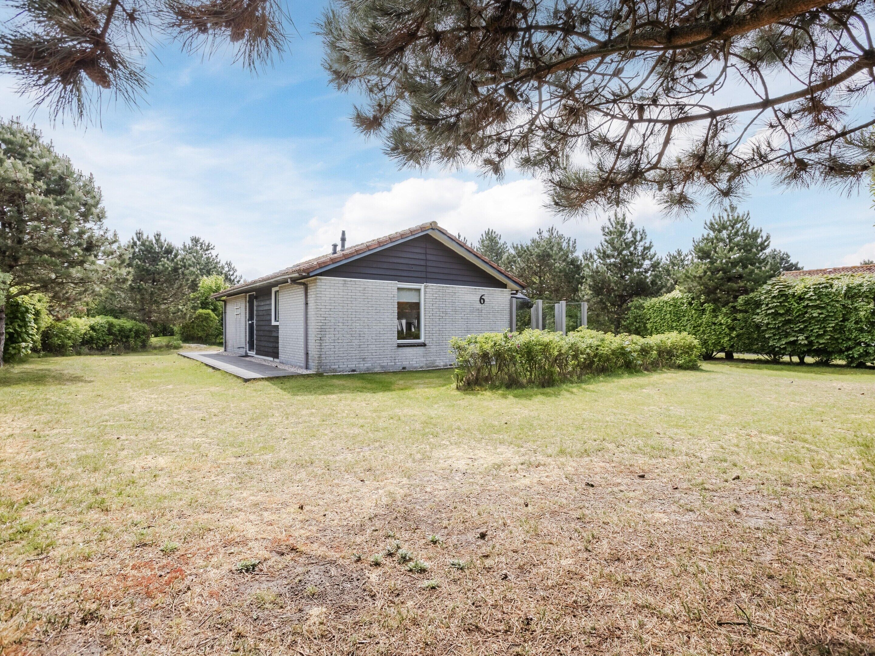 Een gelijkvloers huis met een bakstenen gevel, een klein portaal en een verzorgd gazon.