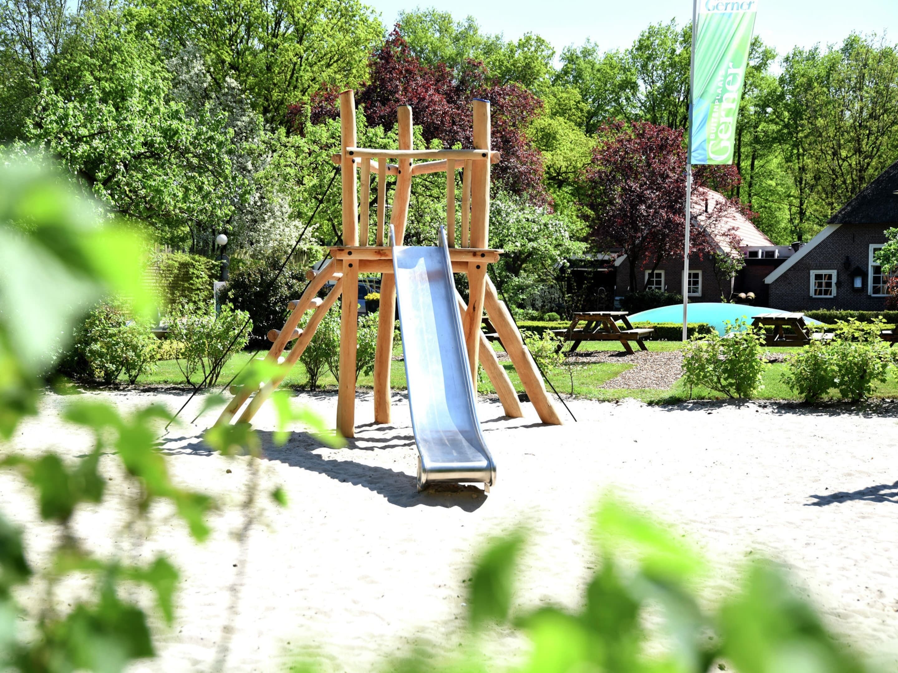 A playground with a wooden swing set and a slide.